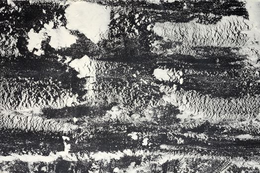 white wheat flour scattered on a black table, top view