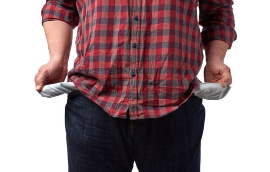 man in a red shirt turned out the empty pockets of his pants, concept of poverty and crisis, unemployment, close up, while background 