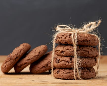 stack of baked round chocolate chip cookies on a brown wooden table, close up