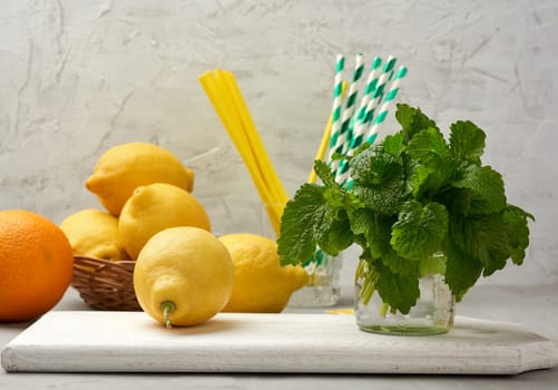 yellow ripe lemon and a bunch of fresh green mint on a wooden board, ingredients for lemonade
