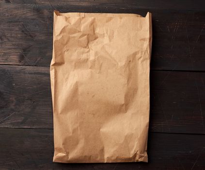 open brown paper bag for food packaging on a brown wooden background, concept of rejection of plastic bags to save the environment