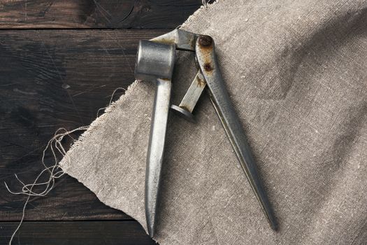 old metal press for garlic and other spices on a brown wooden table, top view