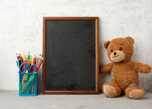 brown teddy bear and empty wooden rectangular frame, chalk board for writing a to-do list. Back to school