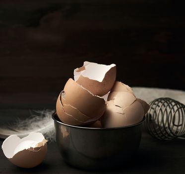 brown raw chicken shell in an iron bowl on a wooden table, close up
