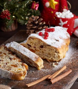 traditional European Stollen cake with nuts and candied fruit on a wooden board, close up