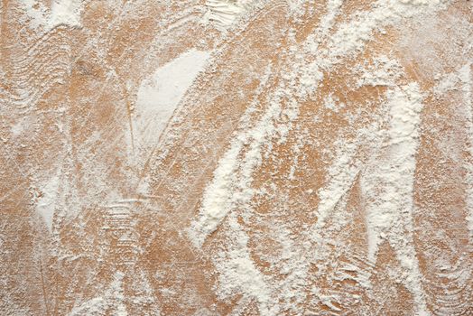 white wheat flour scattered on a brown wooden table, top view