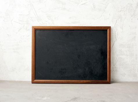 empty wooden rectangular frame, chalk board for writing a to-do list, menu on a white cement background. Back to school