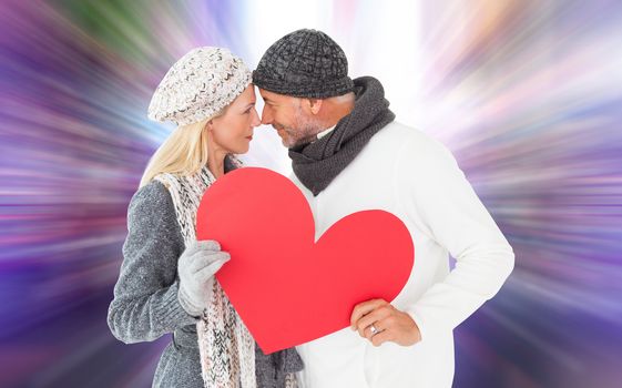 Smiling couple in winter fashion posing with heart shape against glittering screen in urban setting