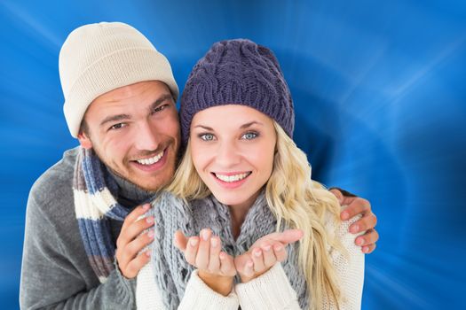 Composite image of attractive couple in winter fashion smiling at camera