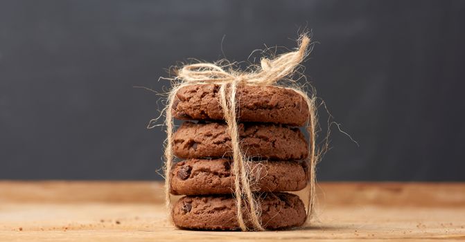 stack of baked round chocolate chip cookies on a wooden background, close up