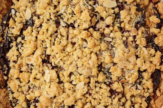 texture of baked crumble pie with blue plum, delicious dessert, top view