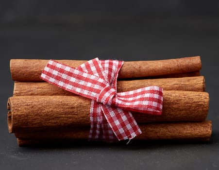 tied bunch of brown cinnamon sticks on a dark background, close up