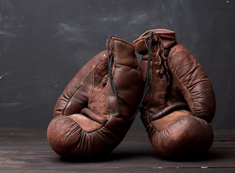 brown leather vintage boxing gloves on a black background, sports equipment