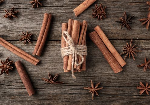 brown cinnamon sticks tied in a bun on a gray wooden background, tasty and fragrant spice, top view