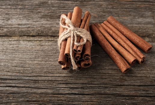 brown cinnamon sticks tied in a bun on a gray wooden background, tasty and fragrant spice, close up