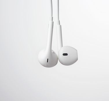 hanging headphones on a white cable, modern gadget on a white background, close up