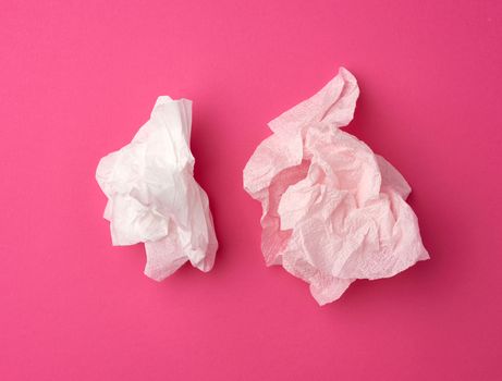crumpled white paper disposable napkins on a pink background, top view