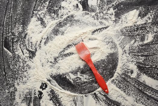 white wheat flour scattered on a black wooden table, top view, kitchen backdrop, copy space