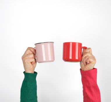 two hands holding ceramic mugs on a white background, copy space, coffee time