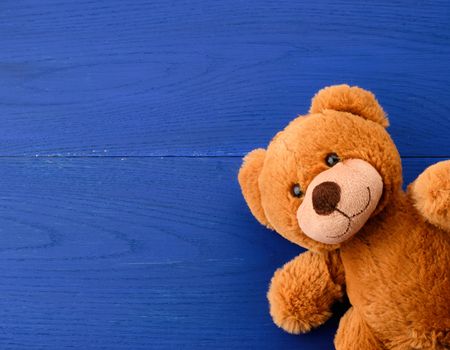 brown teddy bear on a blue wooden background, copy space