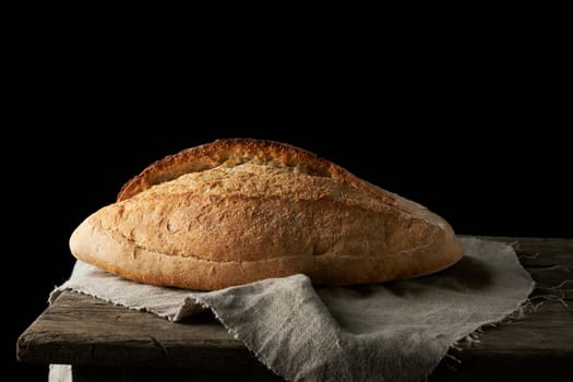 Baked white wheat flour oval crispbread on a wooden board, black background