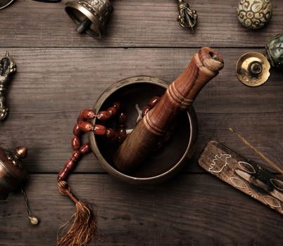 Copper singing bowl, prayer beads, prayer drum and other Tibetan religious objects for meditation and alternative medicine on a brown wooden background
