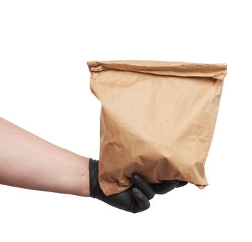 hand in a black latex glove holds a full paper bag of brown craft paper, concept of remote and contactless food delivery, safe receipt of orders, white background 