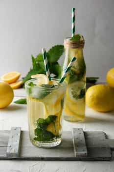 summer refreshing drink lemonade with lemons, mint leaves, lime in a glass, next to the ingredients for making a cocktail