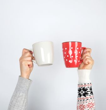 two hands holding ceramic mugs on a white background, copy space, coffee time