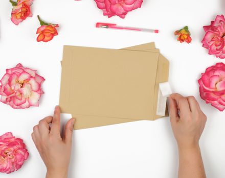 two female hands hold a brown paper envelope, sending letters, top view