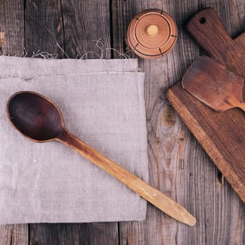 very old empty wooden spoon and rectangular cutting board, top view, gray wooden background 