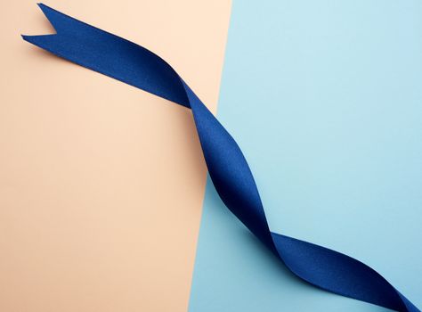 twisted blue satin ribbon on a colored background, top view