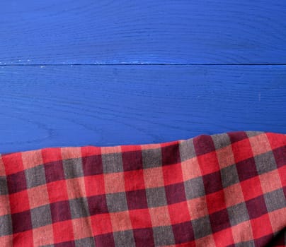 red checkered fabric on a blue wooden background, abstract background, place for an inscription