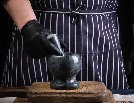 chef man holding a stone mortar and pestle for grinding spices, low key