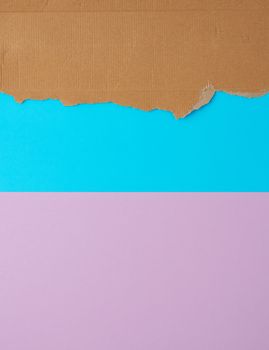 torn edges of corrugated cardboard paper on a blue purple background, abstract template, copy space