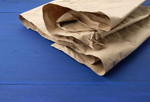 brown crumpled kraft paper sheet on blue wooden background, close up