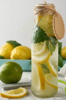 summer refreshing drink lemonade with lemons, mint leaves, lime in a glass bottle, next to the ingredients for making a cocktail