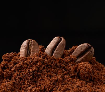 pile of ground roasted coffee arabica and whole grains on a black background, ingredient for a fragrant drink