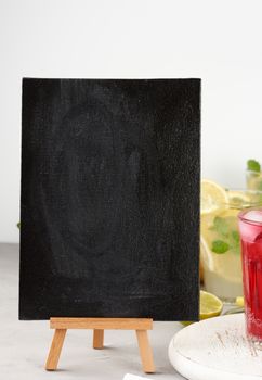 empty black chalk board for writing a summer drink recipe and a glass with berry lemonade, close up