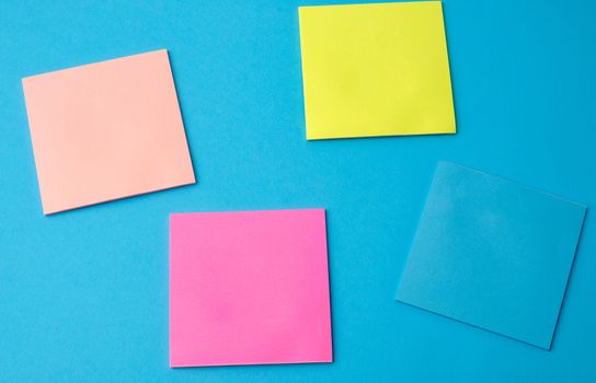 multicolored blank paper stickers of different colors on a blue background, copy space