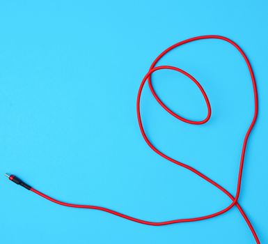 micro cable for charging mobile devices in a red textile braid on a blue background