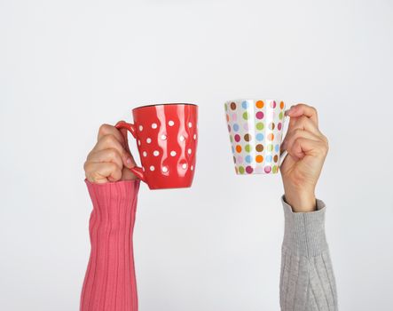 two hands holding ceramic mugs on a white background, copy space, coffee time