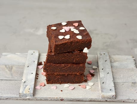 stack of square baked brownie chocolate cake slices on a white background, delicious dessert, close up