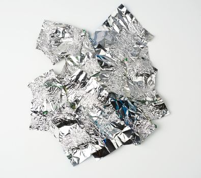 various crumpled foil used candy wrappers on a white background, top view