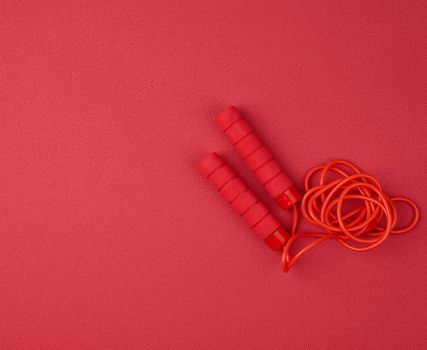 red jump rope lies on a neoprene red sports mat, close up, copy space