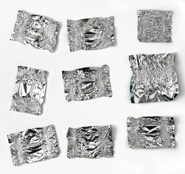 various crumpled foil used candy wrappers on a white background, top view