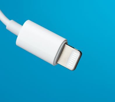 White lightning cable on a blue background, close up