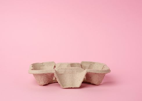 cardboard recycle stand for hot drinks for two cups is on a pink background, close up