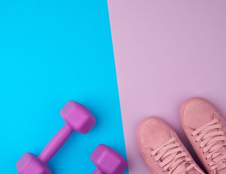 pair of pink leather sneakers, plastic dumbbells for sports on a pink blue background, sports backdrop, top view, copy space