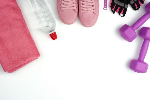 pair of pink leather sneakers, plastic dumbbells and gloves for sports on a white background, sports backdrop, top view, copy space